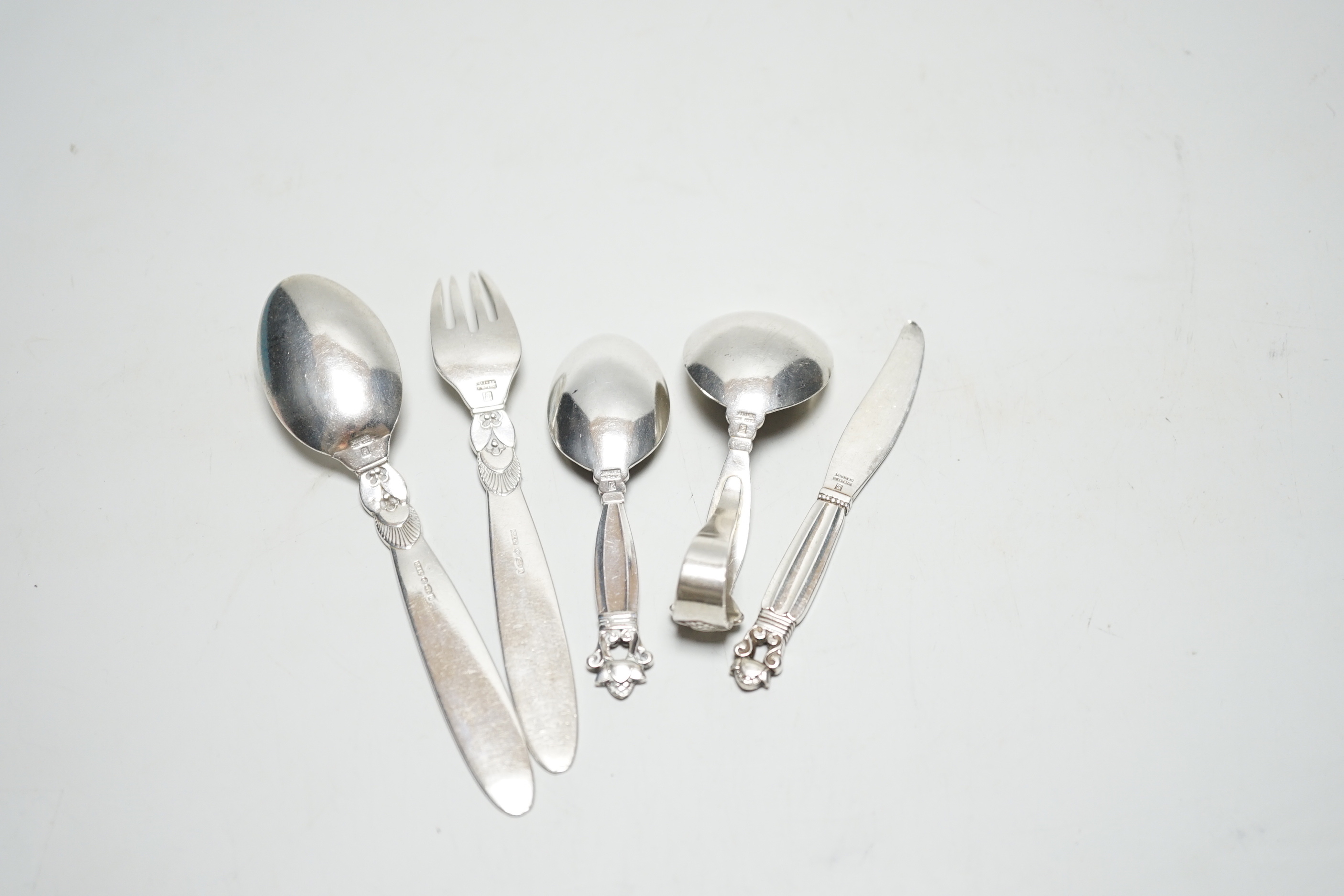 Five assorted items of Georg Jensen flatware including christening fork and spoon, caddy spoon, etc.